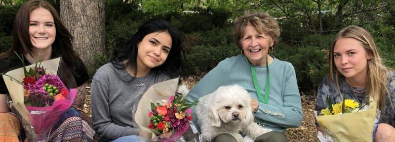 group photo of director Laurie Klith with three young women holding flowers